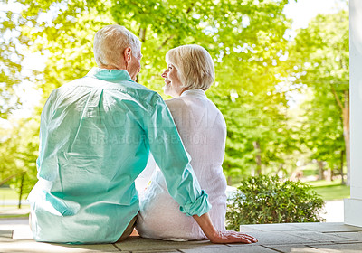 Buy stock photo Rearview shot of an affectionate senior couple sitting outside on their porch during the summer