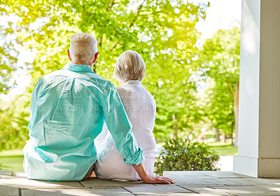 Buy stock photo Rearview shot of an affectionate senior couple sitting outside on their porch during the summer