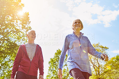 Buy stock photo Low angle shot of an affectionate senior couple taking a walk in the park during the summer