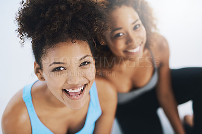 Buy stock photo Portrait shot of two young fit women sitting down and looking at the camera inside of a studio