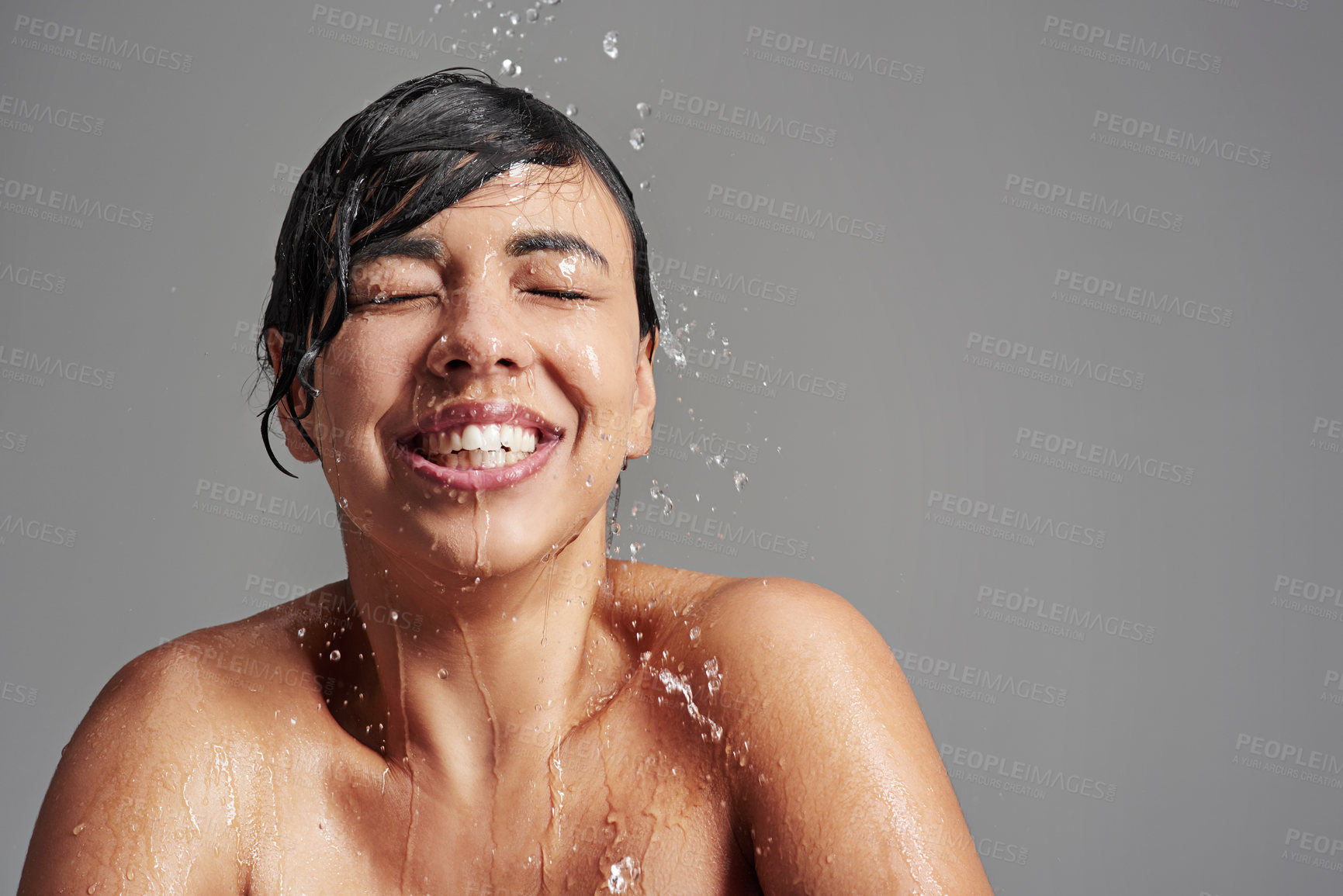 Buy stock photo Shower, cleaning and face of woman with water in studio on gray background for wellness, beauty and grooming. Skincare, bathroom and happy female person with splash for washing, hygiene and cleansing