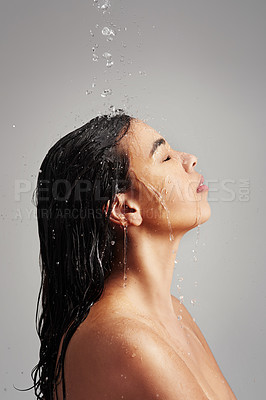 Buy stock photo Studio shot of a young woman enjoying a shower against a gray background