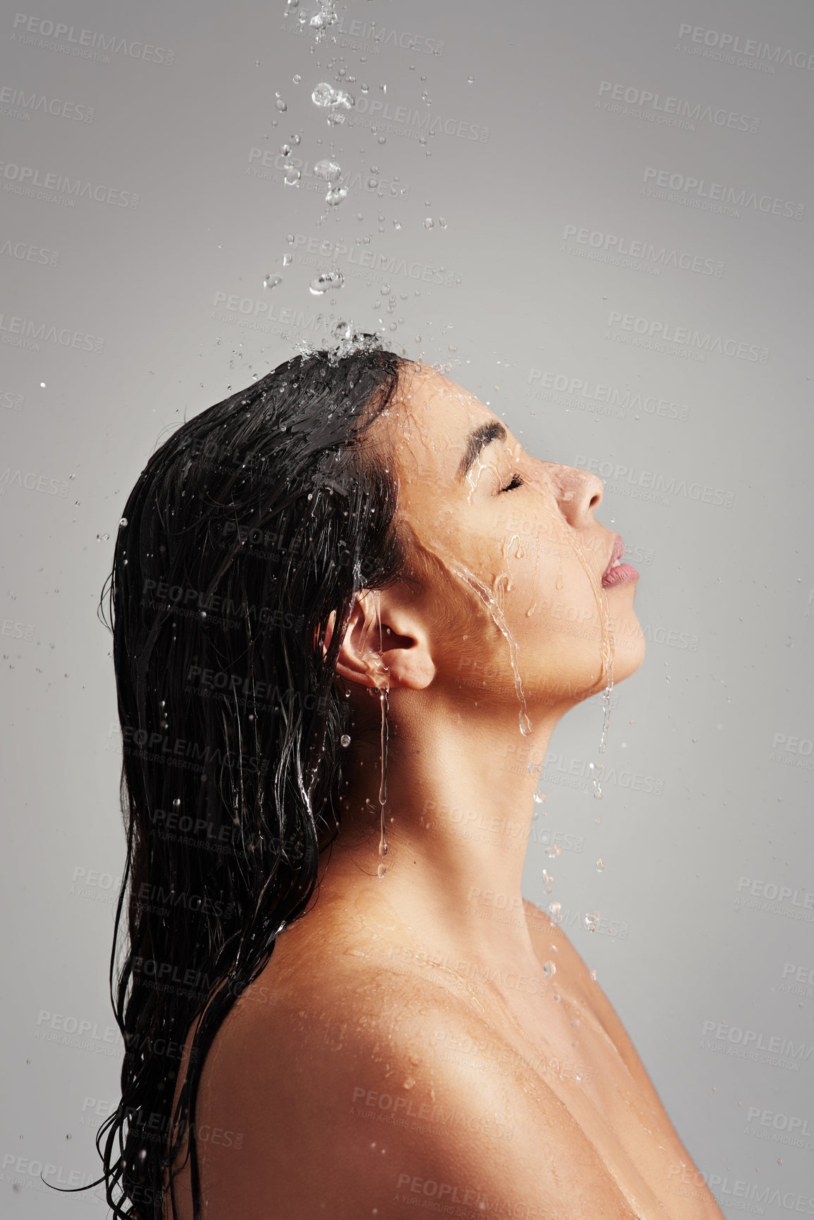 Buy stock photo Studio shot of a young woman enjoying a shower against a gray background