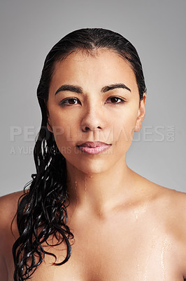Buy stock photo Studio shot of a young woman with wet hair posing against a gray background