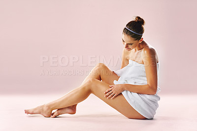 Buy stock photo Studio, skincare and girl in towel, body and beauty with cosmetics, results and smile for treatment. Pink background, wellness and person with care for legs, glow and shine of skin, soft and relax