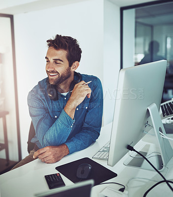 Buy stock photo High angle shot of a handsome young businessman looking thoughtful while working on his computer in the office