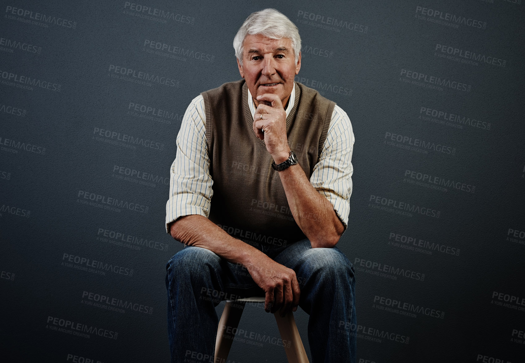 Buy stock photo Studio portrait of a handsome mature man looking thoughtful while sitting on a stool against a dark background