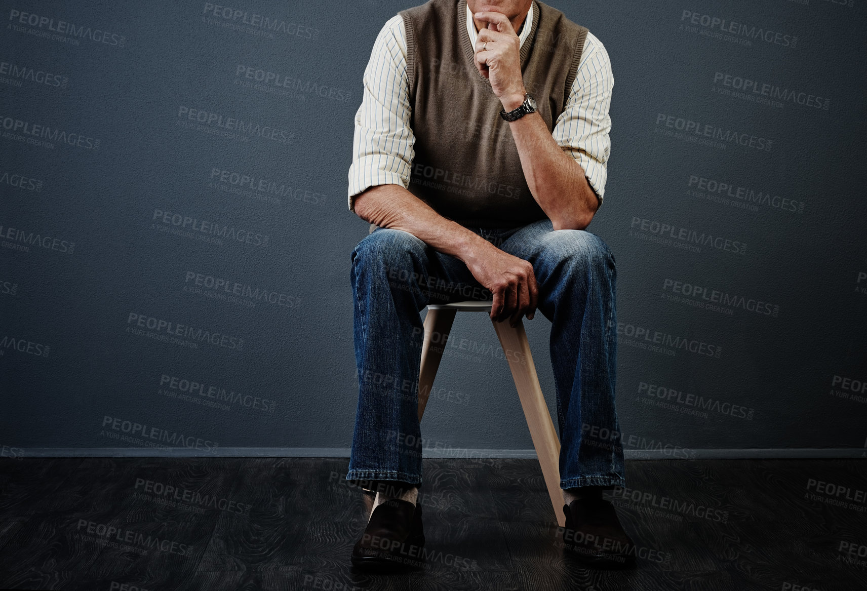 Buy stock photo Studio shot of an unrecognizable man looking thoughtful while sitting on a stool against a dark background