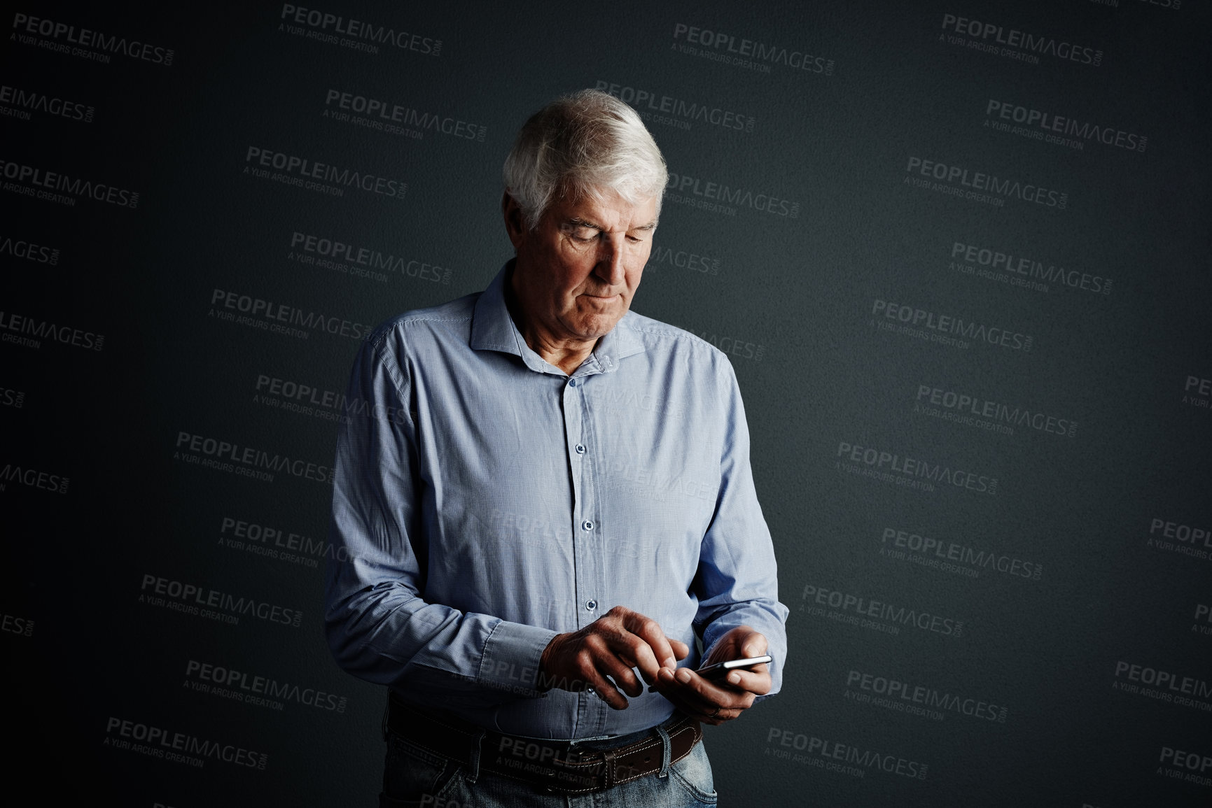 Buy stock photo Studio shot of a handsome mature man sending a text message against a dark background
