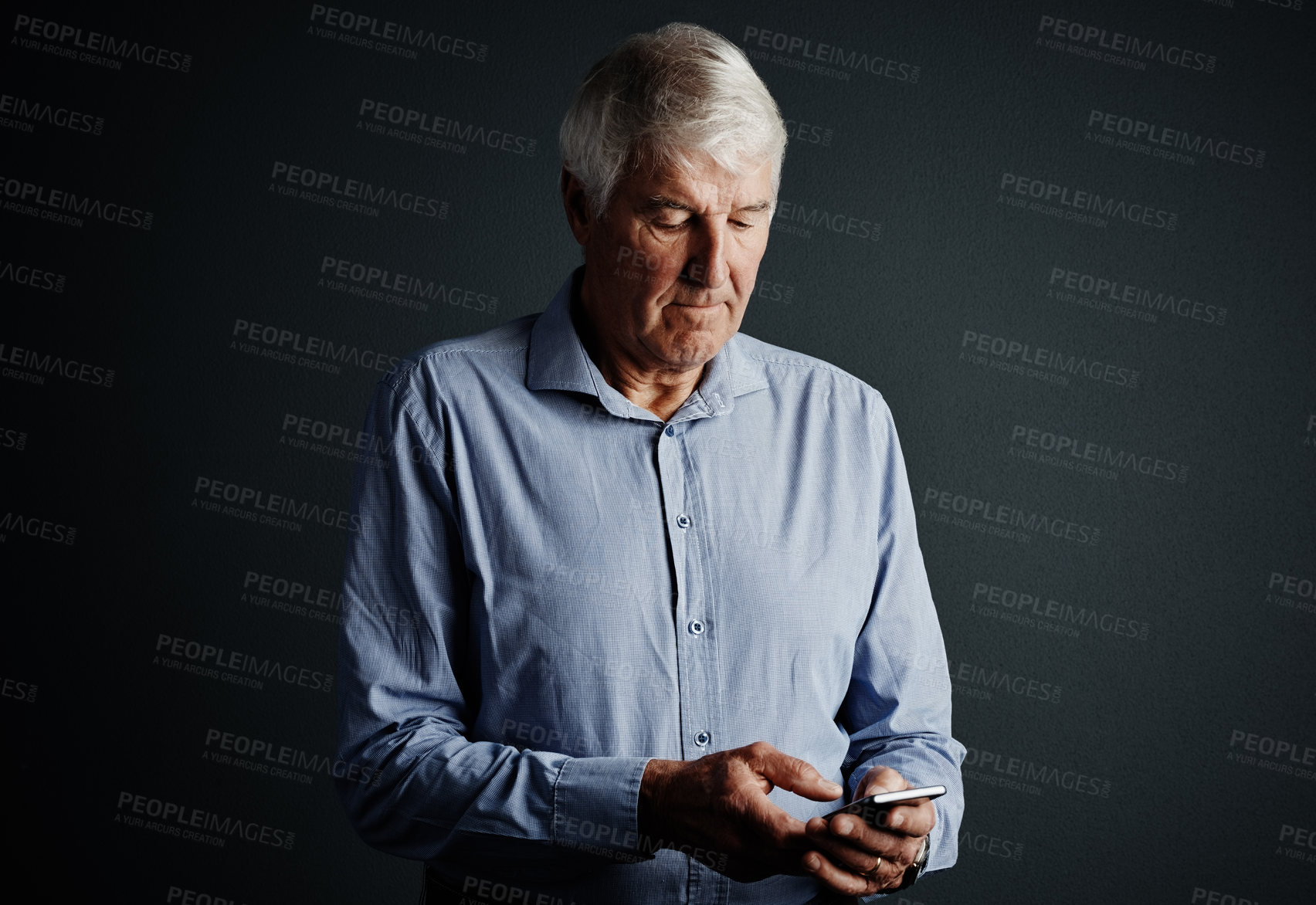 Buy stock photo Studio shot of a handsome mature man sending a text message against a dark background