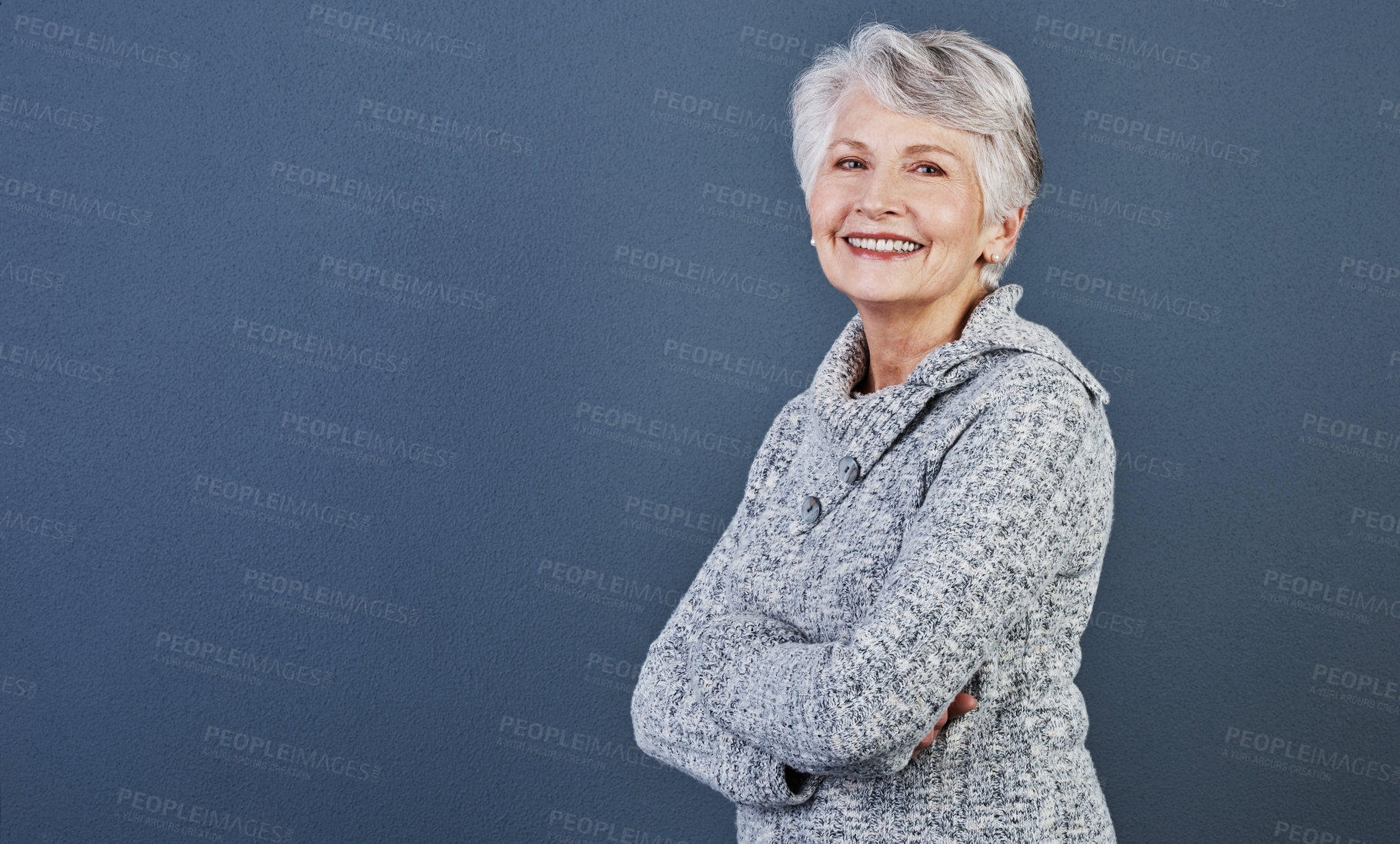 Buy stock photo Studio shot of a cheerful elderly woman standing with her arms folded while looking  at the camera