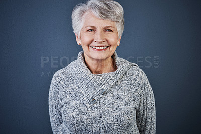 Buy stock photo Studio shot of a cheerful elderly woman standing with her hands behind her back while looking at the camera