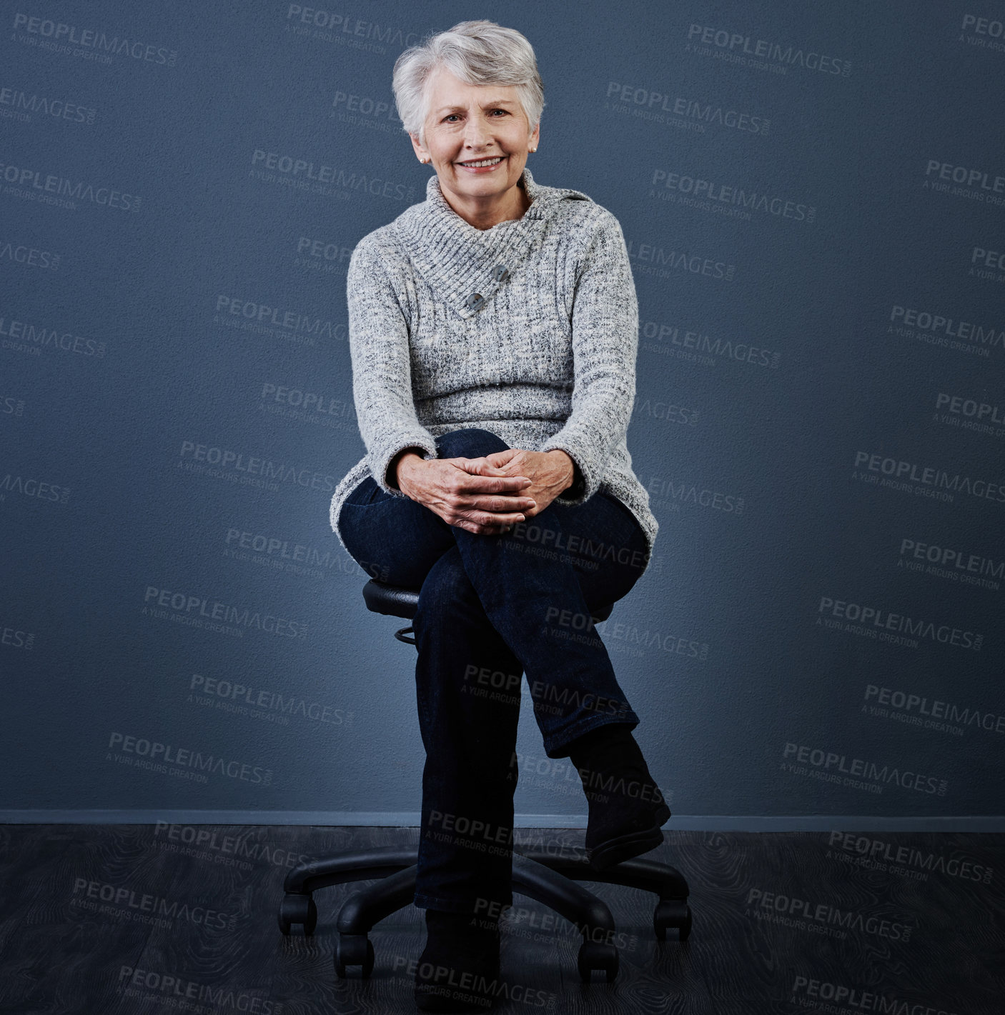 Buy stock photo Studio shot of a cheerful elderly woman sitting with her legs crossed while looking at the camera