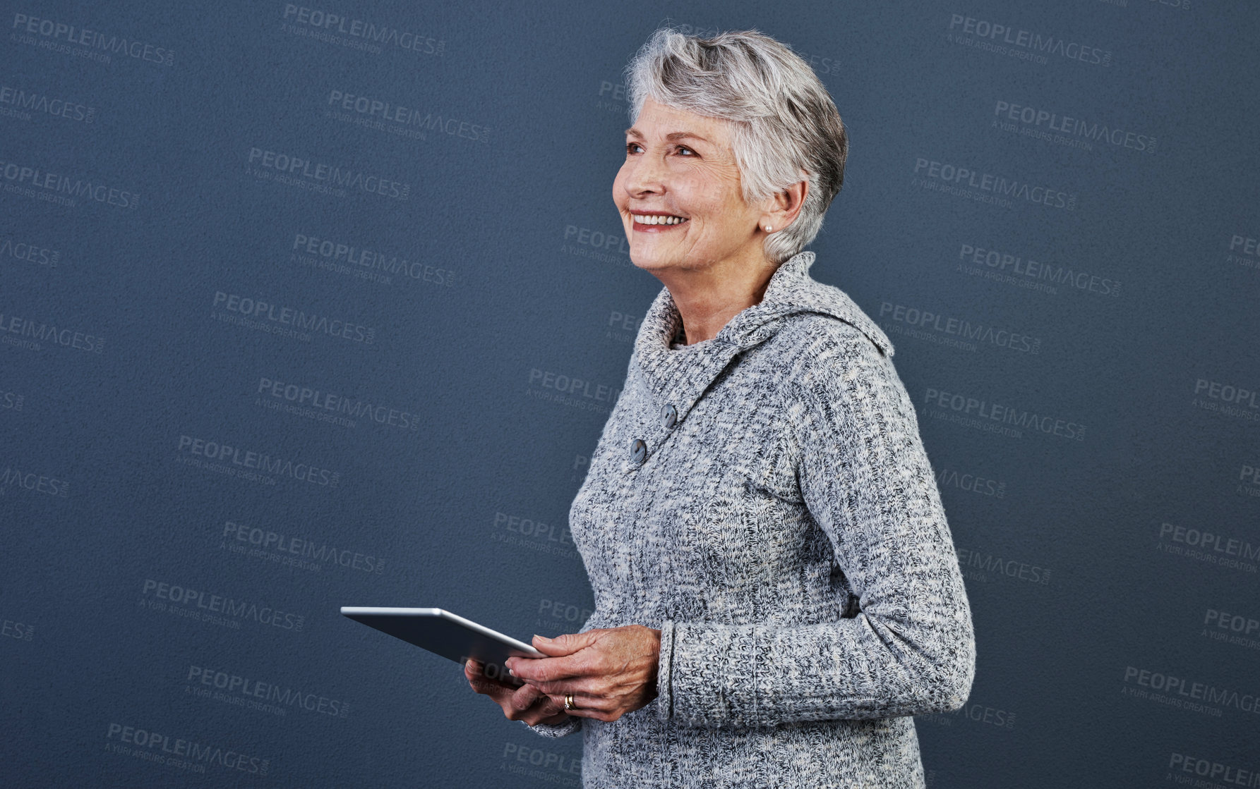 Buy stock photo Studio shot of an cheerful elderly woman standing and using a tablet