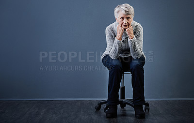 Buy stock photo Studio shot of an elderly woman sitting with her hands under her chin while looking at the camera