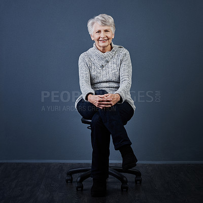 Buy stock photo Studio shot of a cheerful elderly woman sitting with her legs crossed while looking at the camera