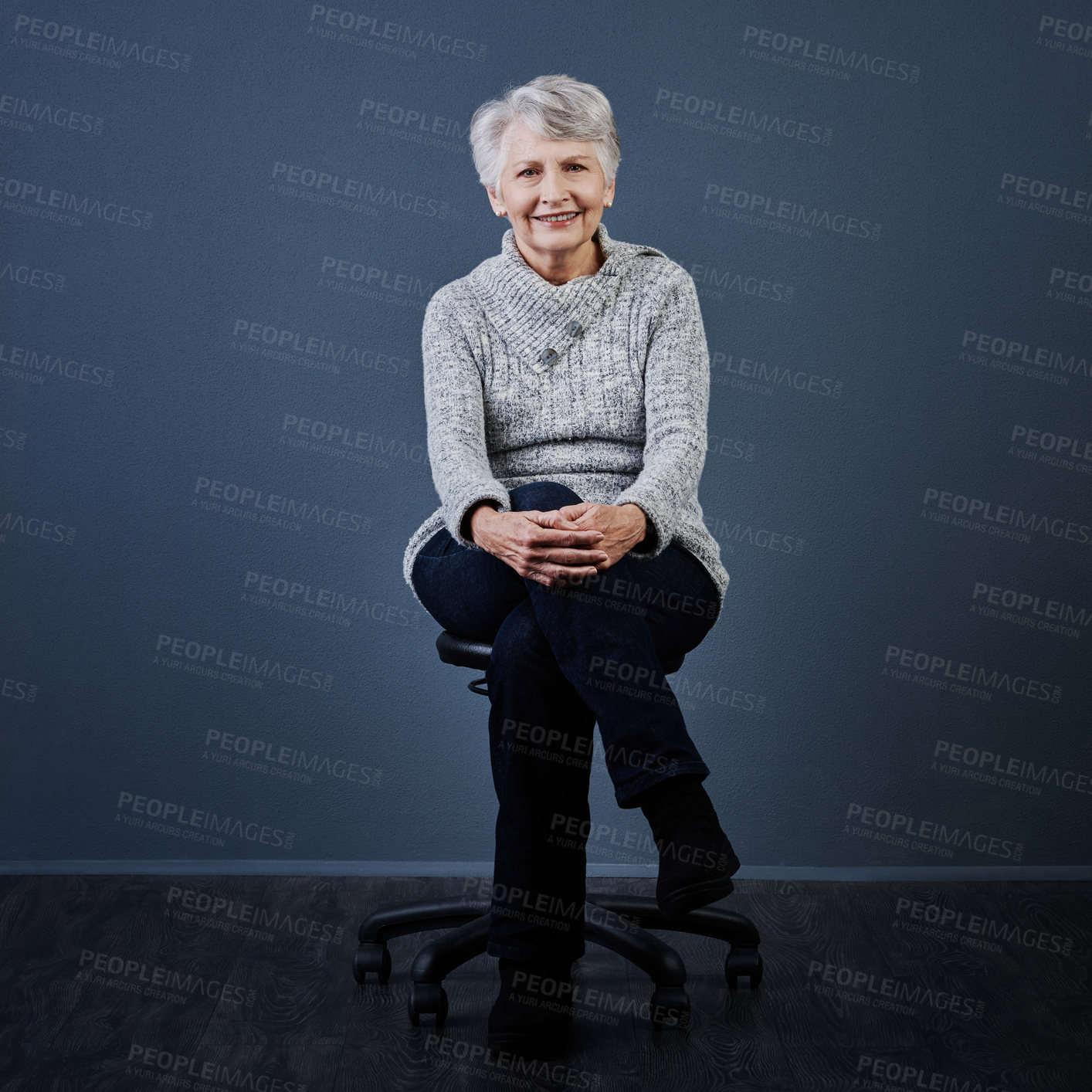 Buy stock photo Studio shot of a cheerful elderly woman sitting with her legs crossed while looking at the camera