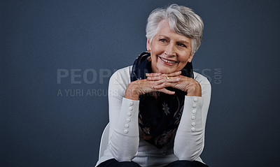 Buy stock photo Studio shot of cheerful elderly woman sitting with her hands under her chin while looking into the distance