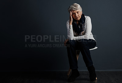 Buy stock photo Studio shot of a stressed out elderly woman sitting down and contemplating while looking into the distance