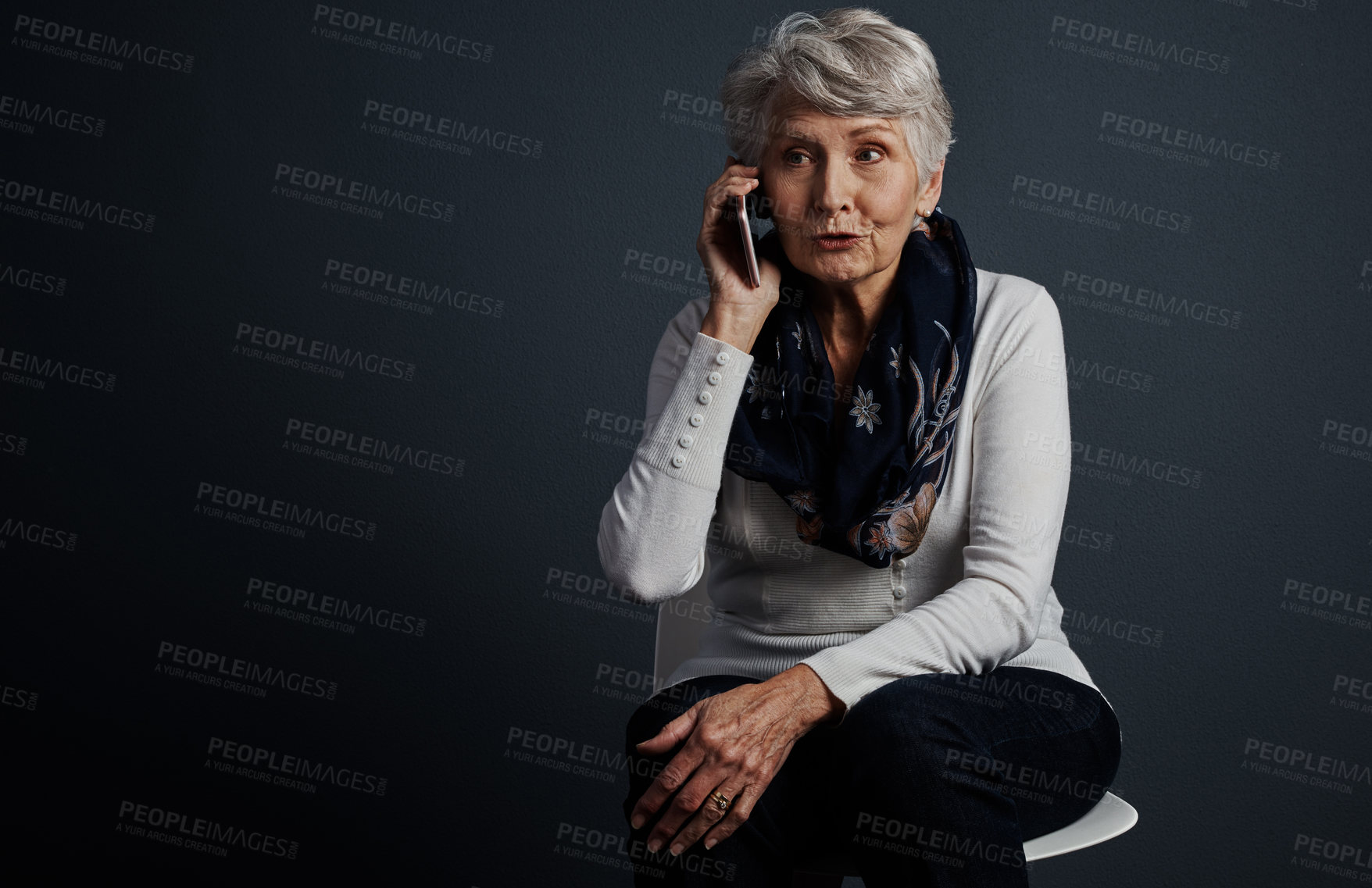 Buy stock photo Studio shot of a cheerful elderly woman sitting down and talking on her cellphone