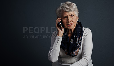 Buy stock photo Studio shot of an elderly woman sitting down and talking on her cellphone