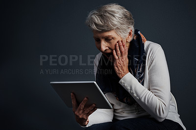 Buy stock photo Studio shot of an cheerful elderly woman standing and using a tablet