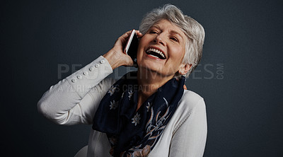 Buy stock photo Studio shot of a cheerful elderly woman sitting down and talking on her cellphone