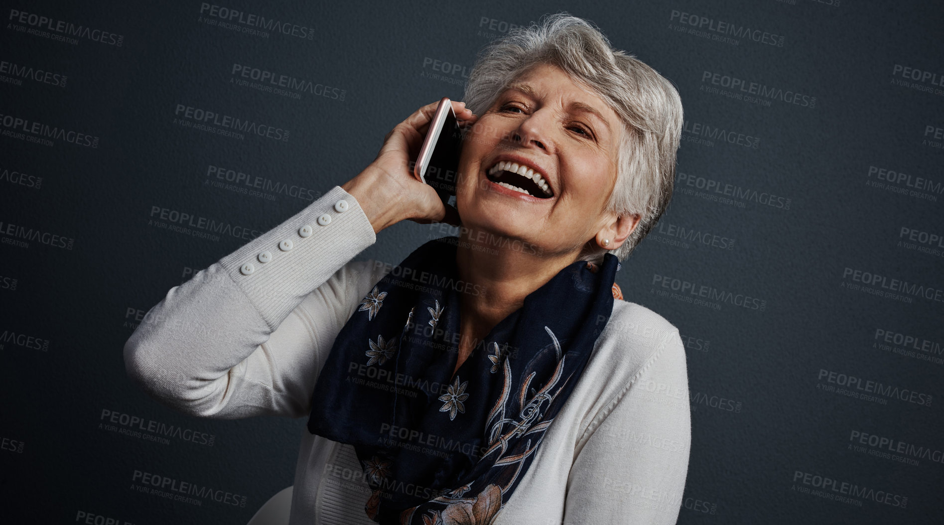 Buy stock photo Studio shot of a cheerful elderly woman sitting down and talking on her cellphone