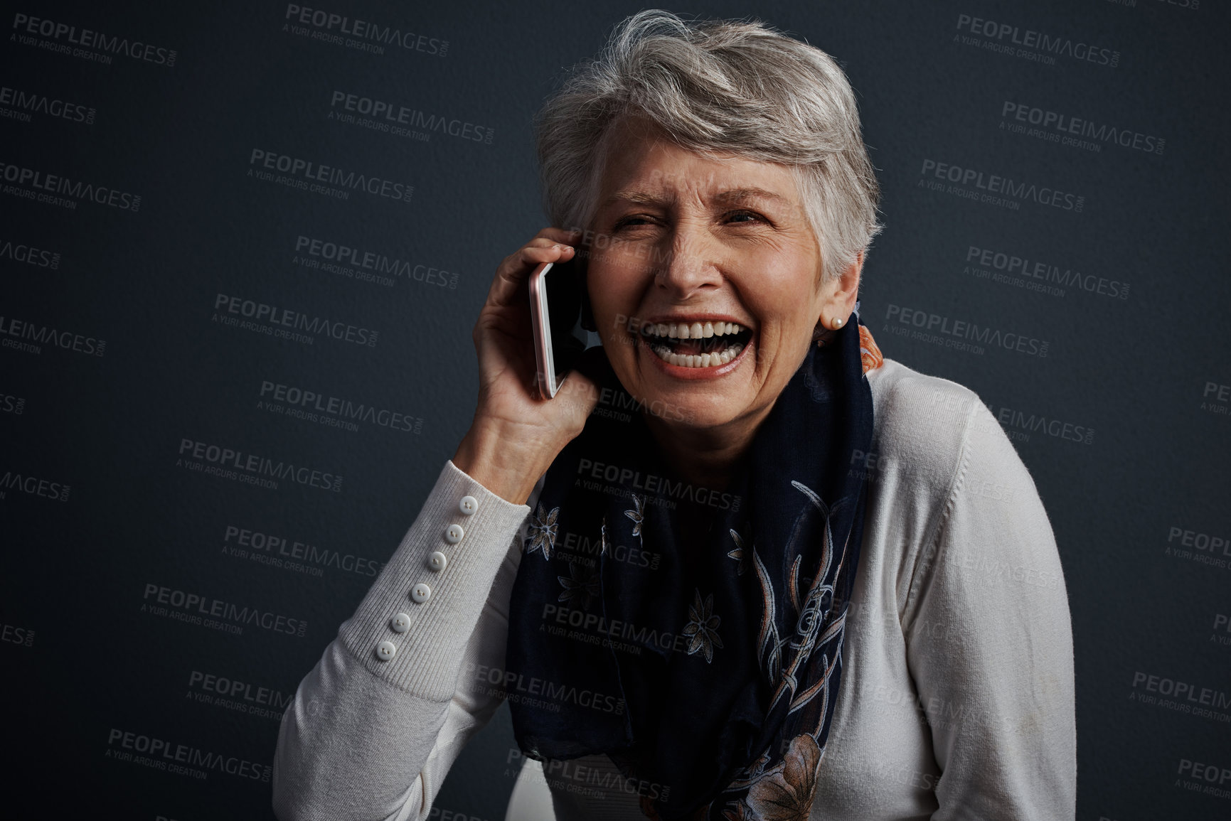 Buy stock photo Studio shot of a cheerful elderly woman sitting down and talking on her cellphone