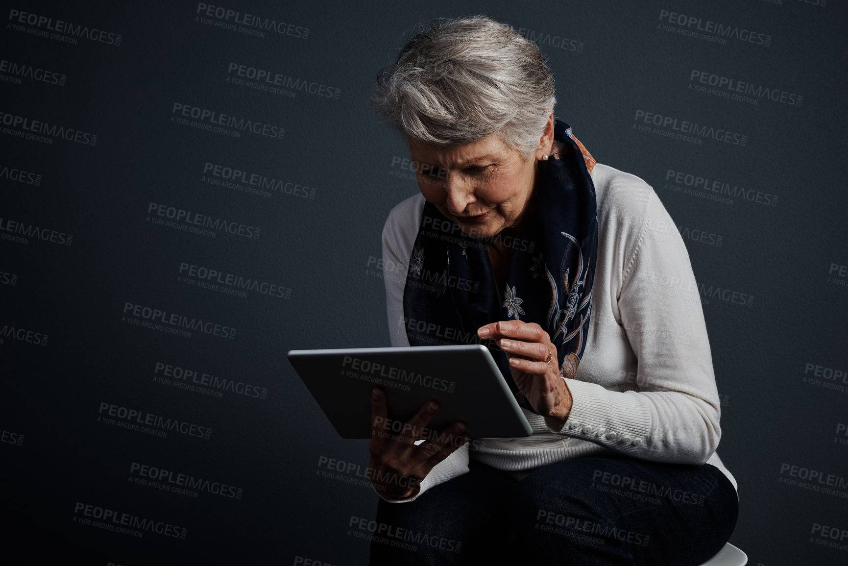 Buy stock photo Studio shot of an  elderly woman sitting and using a tablet