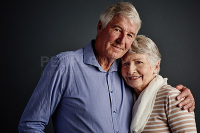Buy stock photo Studio portrait of an affectionate senior couple posing against a grey background