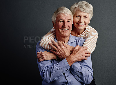 Buy stock photo Studio portrait of an affectionate senior couple posing against a grey background