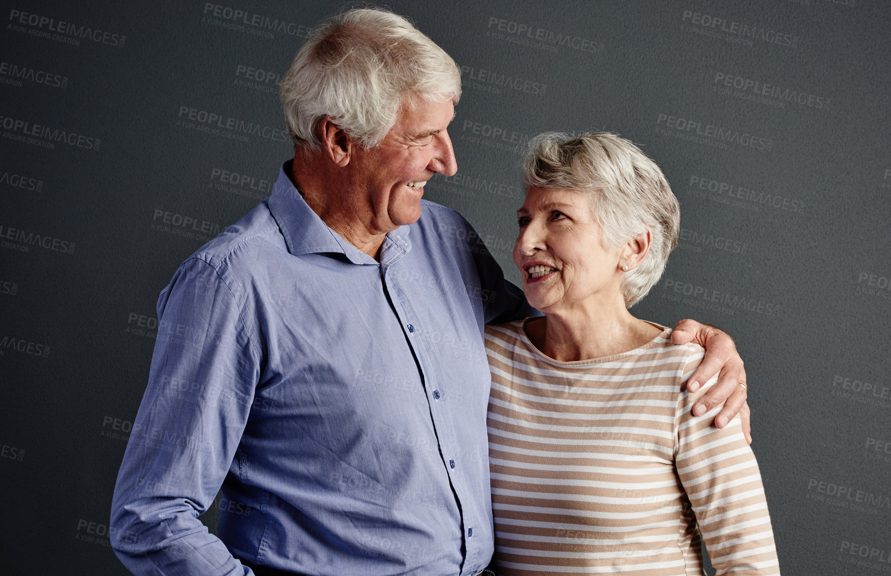 Buy stock photo Studio shot of an affectionate senior couple posing against a grey background