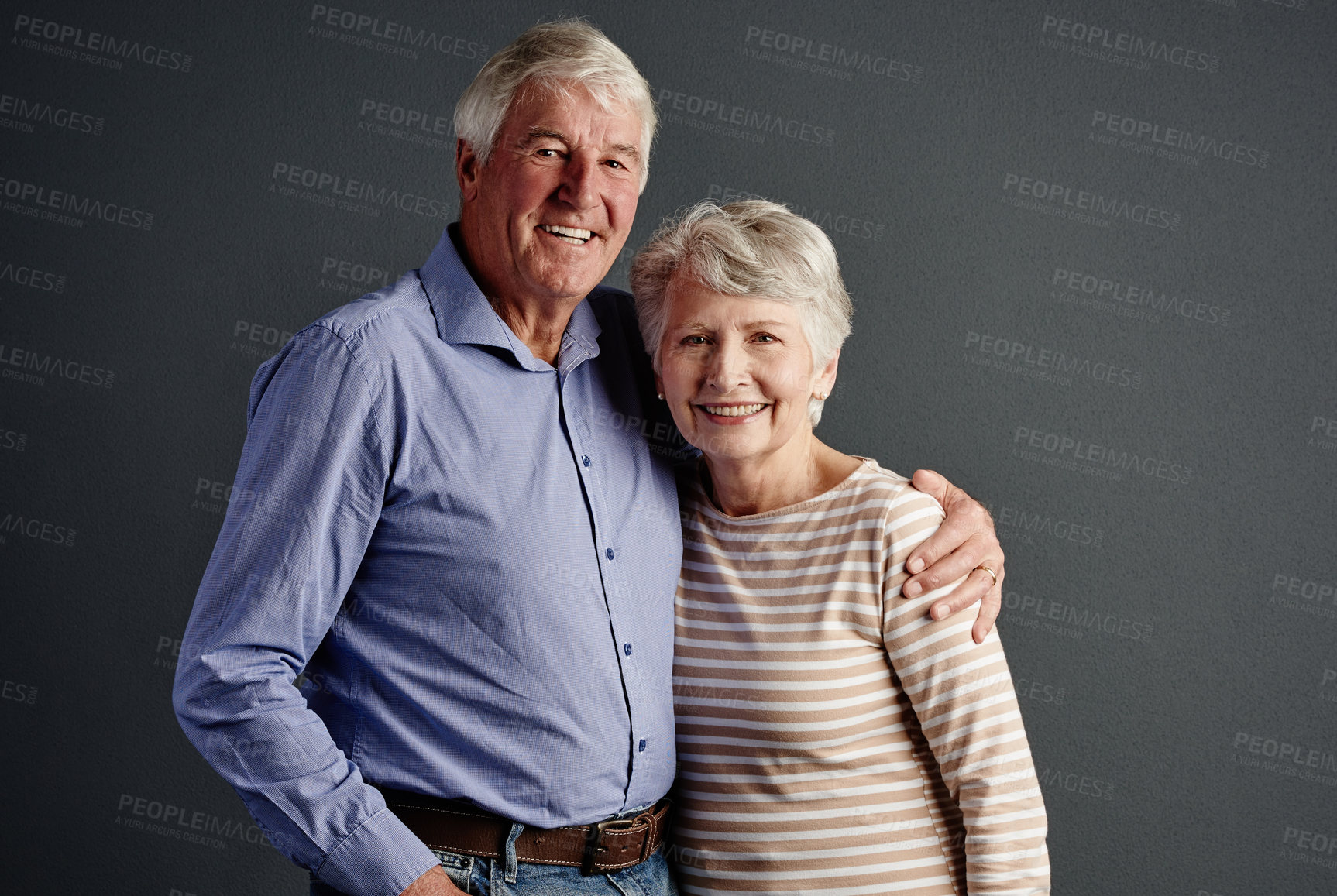 Buy stock photo Studio portrait of an affectionate senior couple posing against a grey background