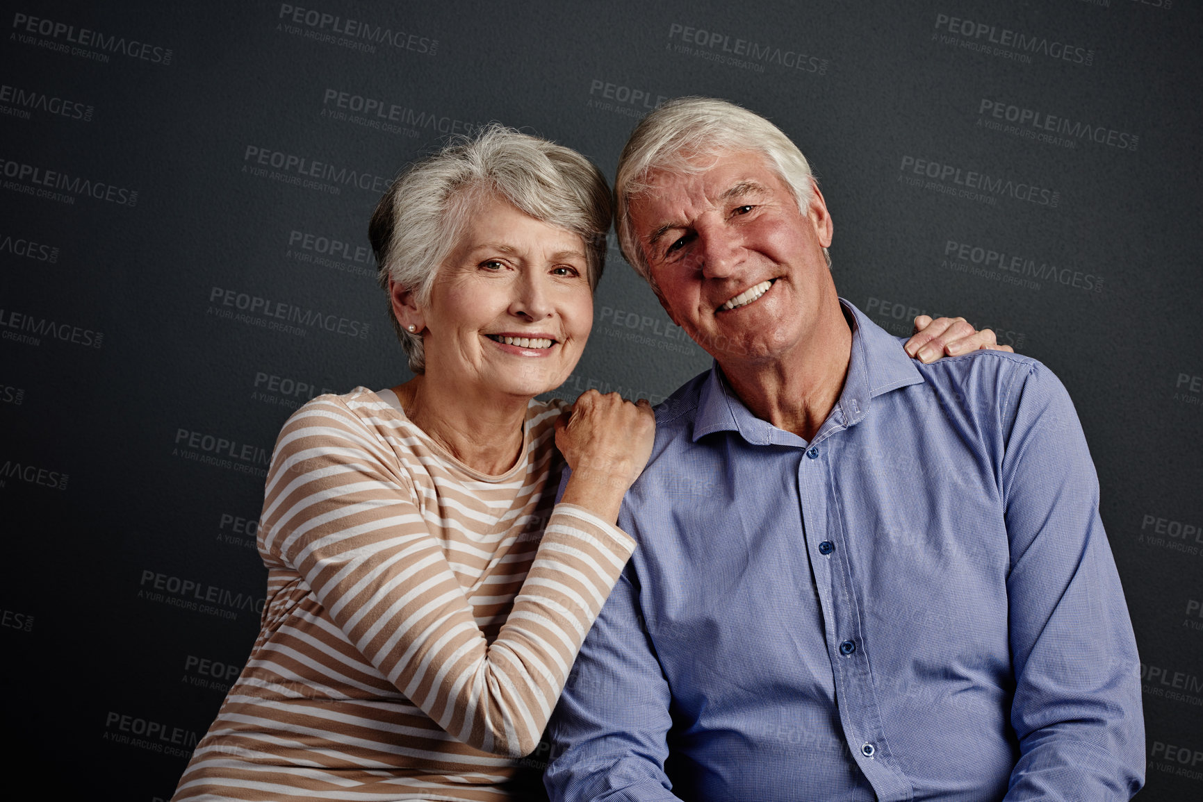 Buy stock photo Studio portrait of an affectionate senior couple posing against a grey background