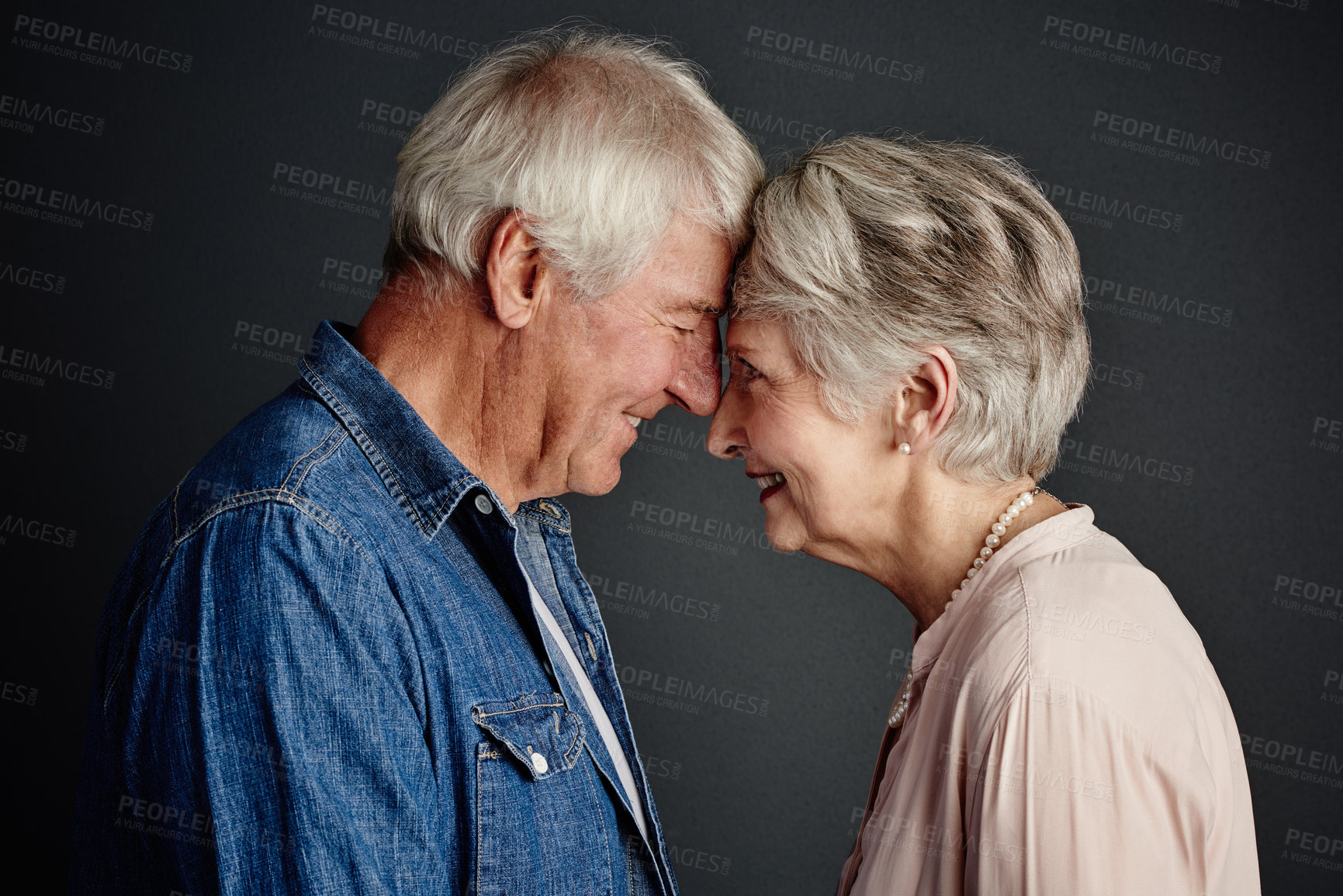 Buy stock photo Studio shot of an affectionate senior couple posing against a grey background