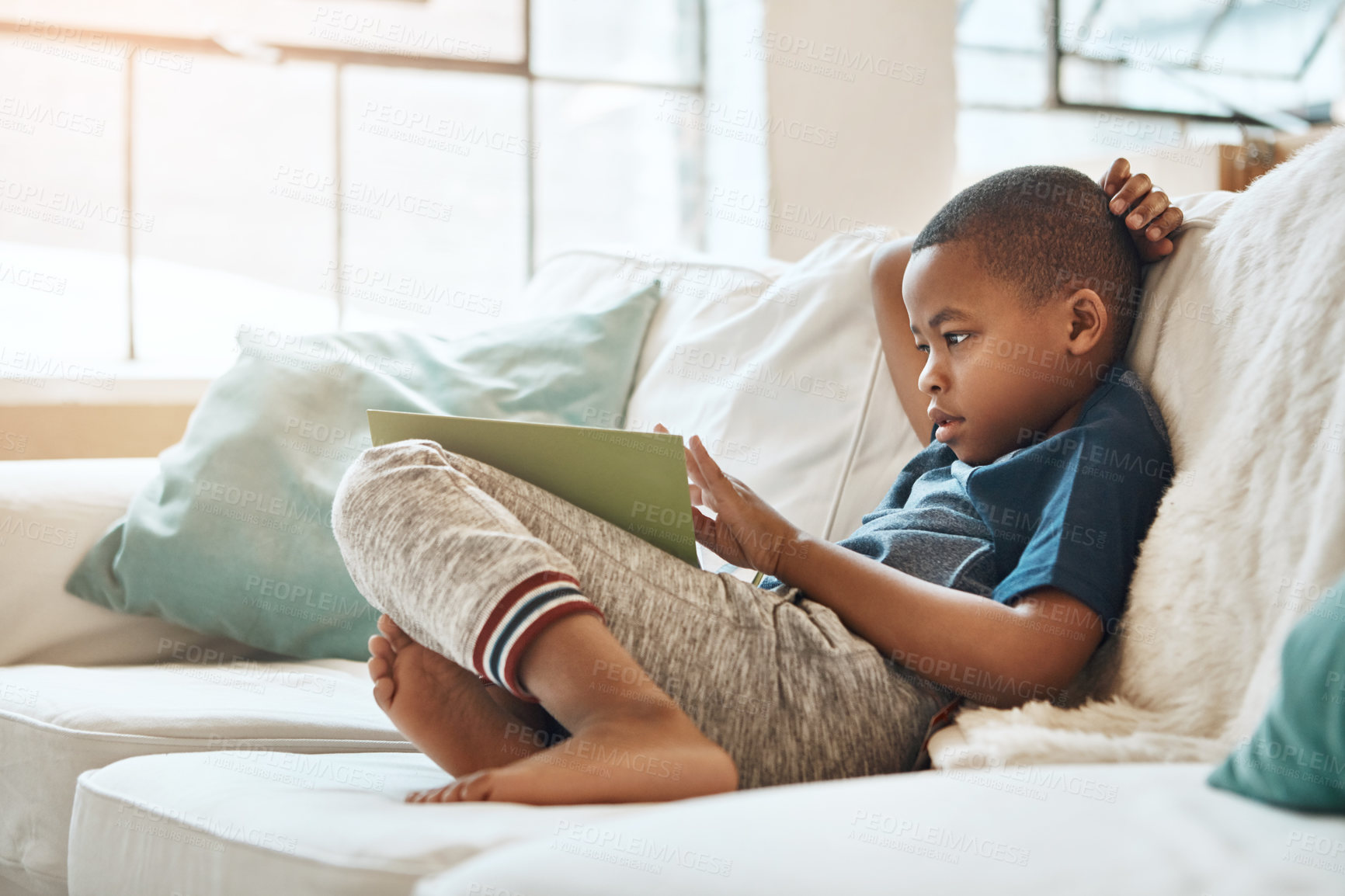 Buy stock photo Shot of a little boy reading a book at home