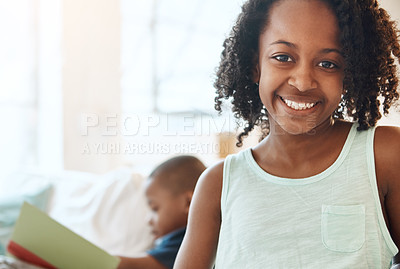 Buy stock photo Shot of a little boy reading a book and his sister smiling at home