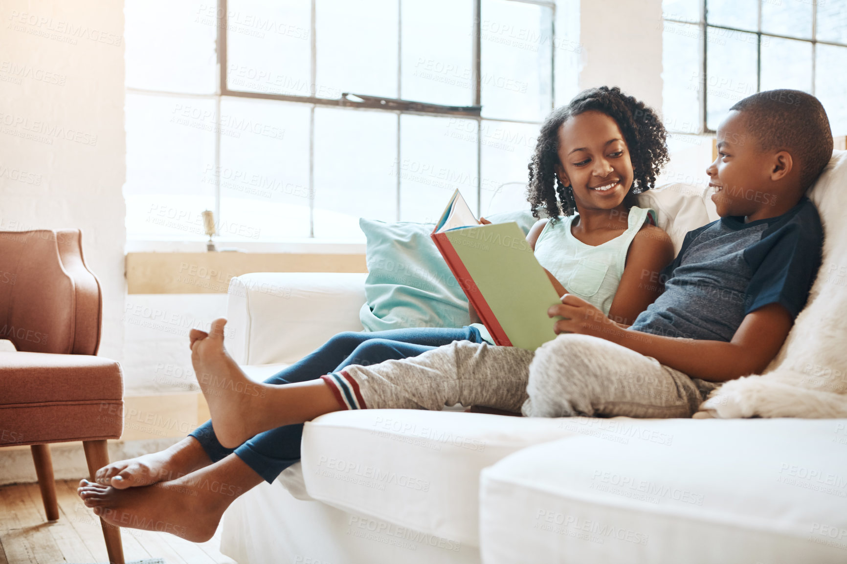 Buy stock photo Shot of a little brother and sister reading a book indoors