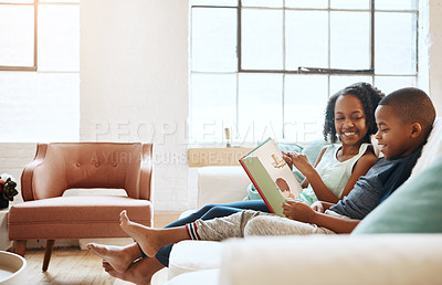 Buy stock photo Shot of a little brother and sister reading a book indoors