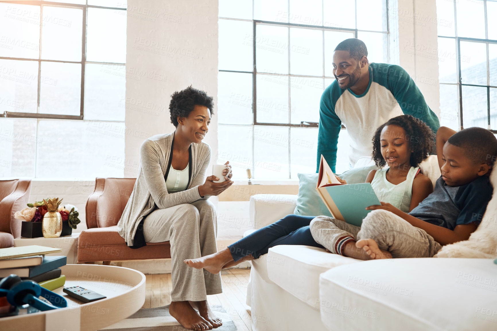 Buy stock photo Shot of a little brother and sister reading a book while their parents watch at home