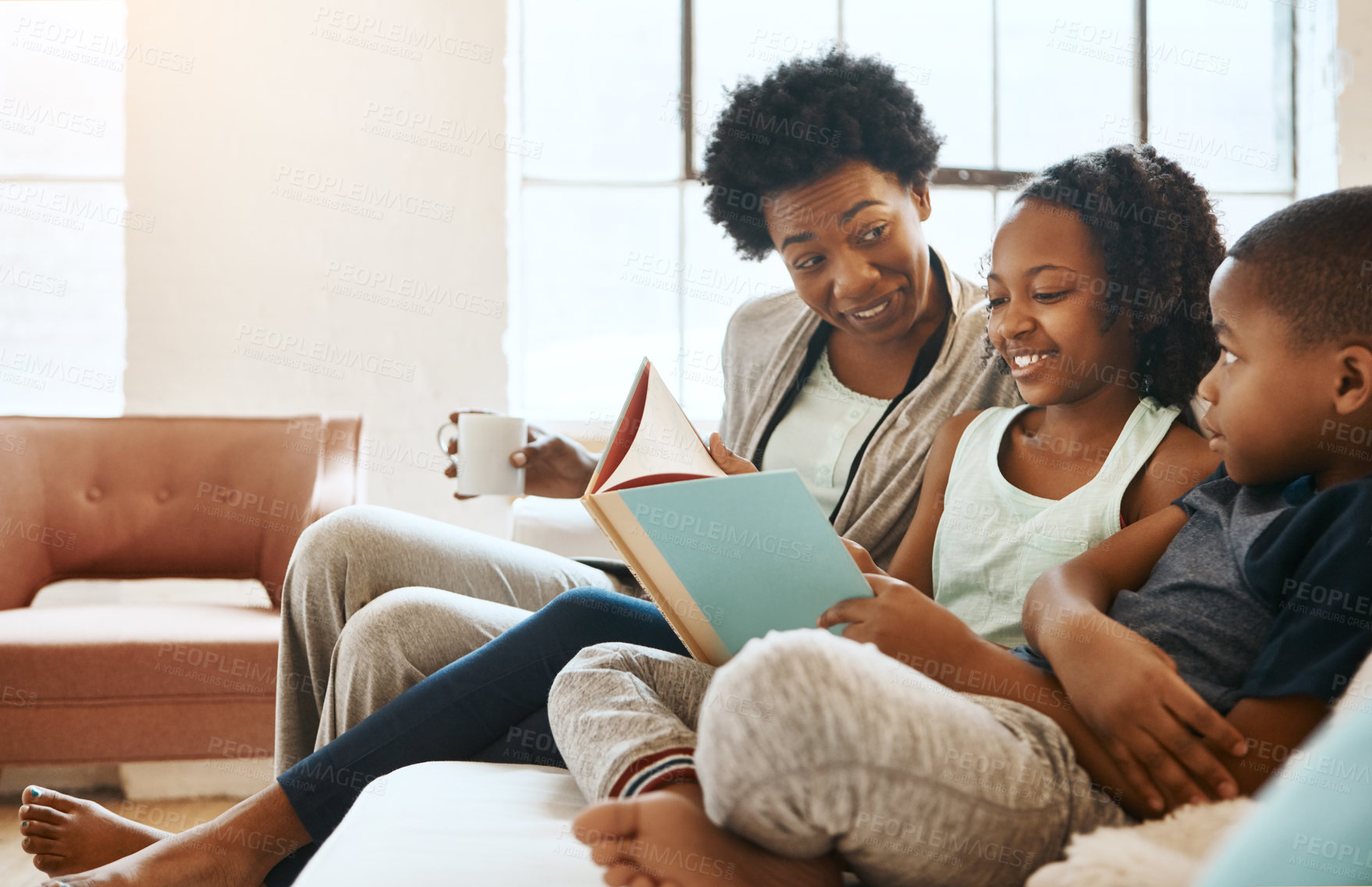 Buy stock photo Shot of a little brother and sister reading a book while their mother watches at home