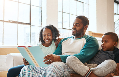 Buy stock photo Shot of a father and his children reading a book indoors