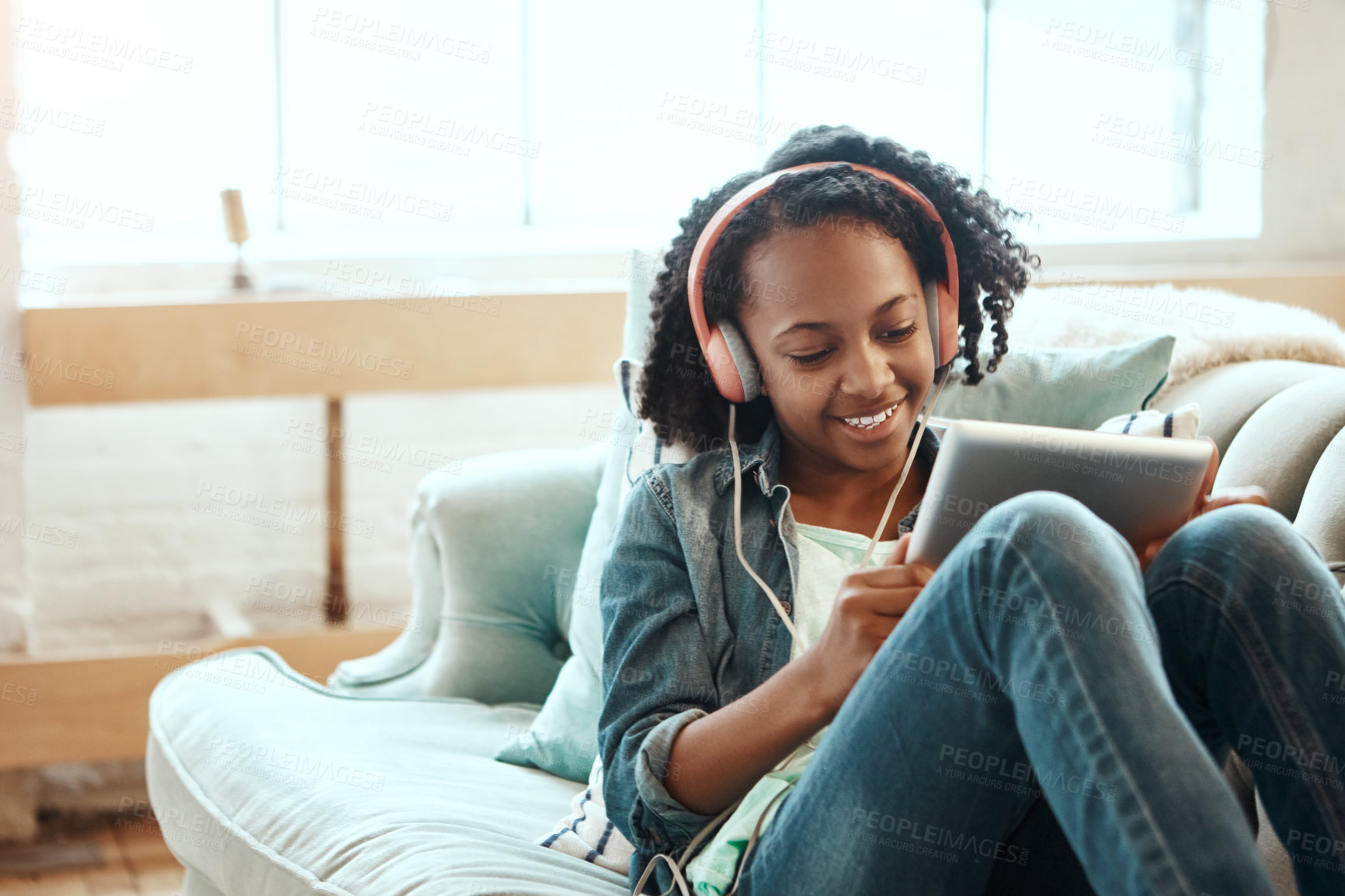 Buy stock photo Happy girl, headphones and music with tablet on sofa for online streaming, entertainment or listening at home. Young female person, child or teenager in relax with smile on technology for audio