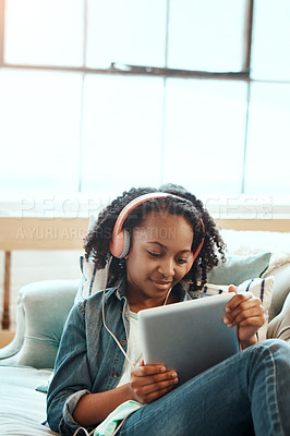 Buy stock photo Tablet, headphones and black girl on the sofa to relax while listening to music, radio or podcast. Rest, technology and African child watching a video or movie on mobile device in living room at home