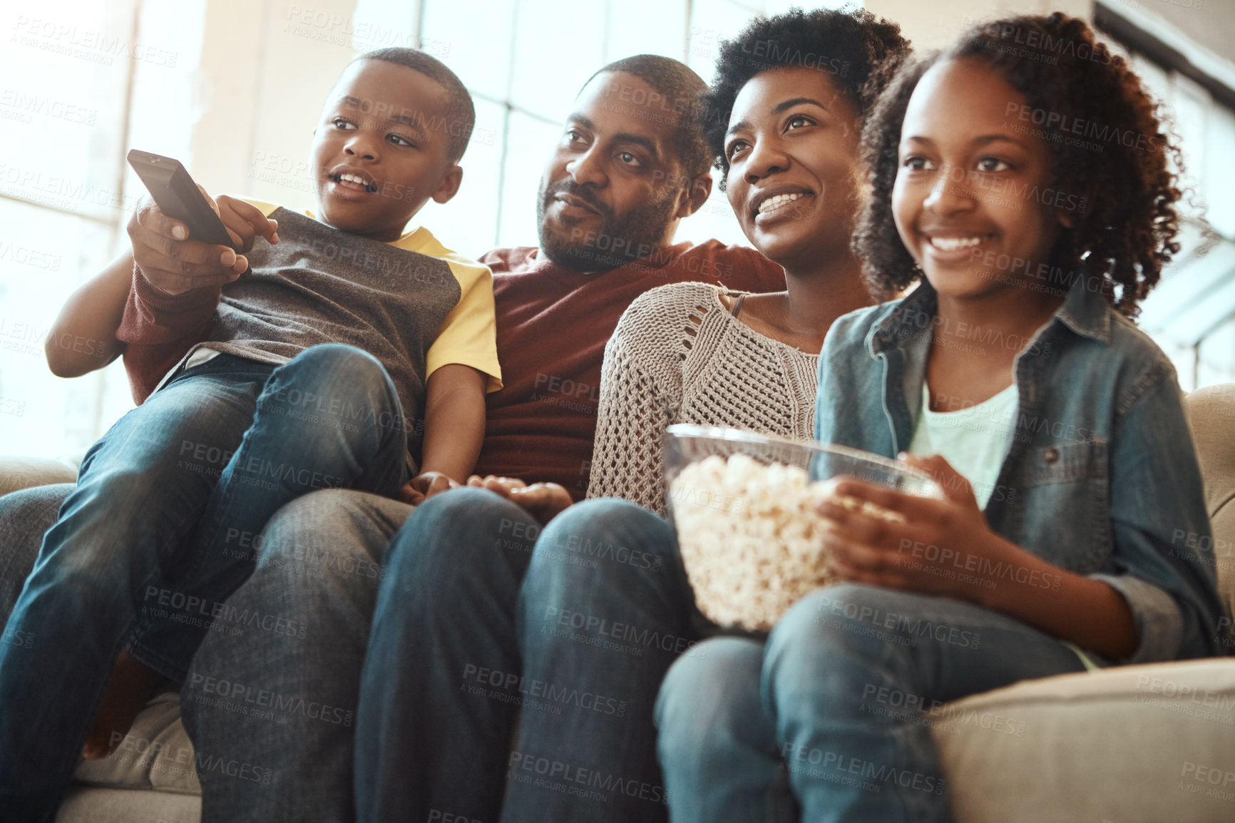 Buy stock photo Black family watching tv on sofa for movie, film and cartoon together, bonding and quality time in living room. Popcorn, kids television show of people, mother and father with kids, on couch watching