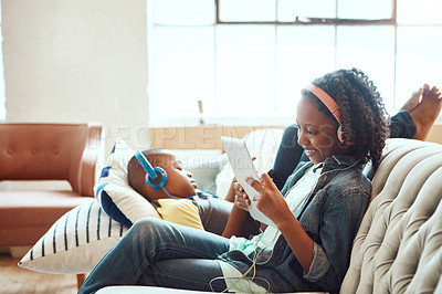 Buy stock photo Siblings, tablet and headphones for relax on sofa in the living room enjoying entertainment or wifi at home. Happy sister and brother relaxing on couch listening to music or online streaming indoors