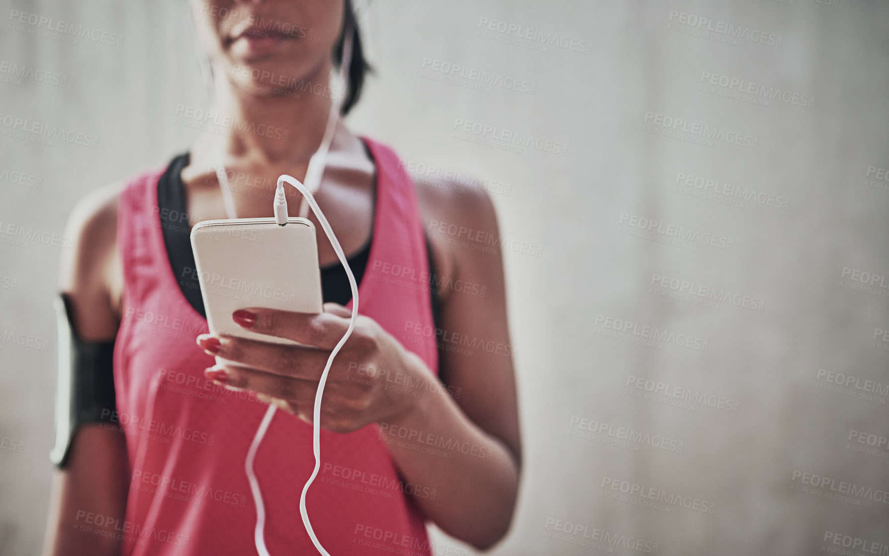 Buy stock photo Shot of a sporty young woman listening to music while exercising outdoors