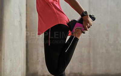 Buy stock photo Shot of an unrecognisable woman stretching her legs while exercising outdoors