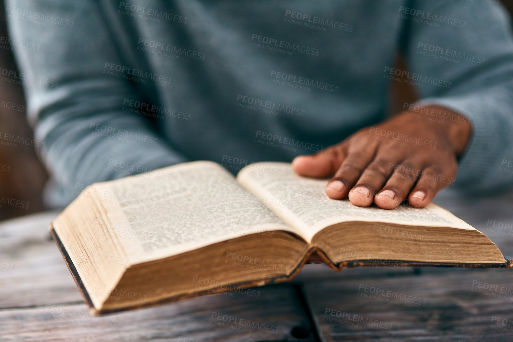 Buy stock photo Hands, faith and a man reading the bible at a table outdoor in the park for religion or belief in god. Book, story and spiritual with a male christian sitting in the garden for study or worship